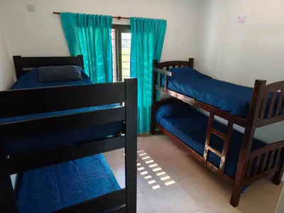 two bunk beds in a room with blue curtains at Casa de campo Los Gurises in Alta Gracia