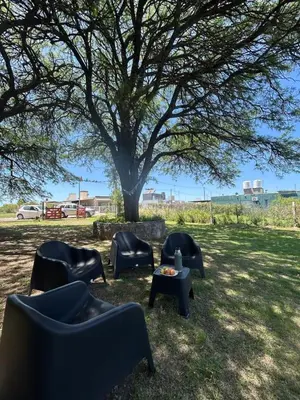 a group of chairs and a table under a tree at Casa de campo Los Gurises in Alta Gracia
