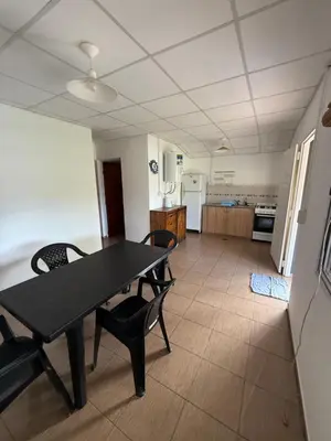 a dining room with a table and chairs and a kitchen at Cabañas Marquetti in Potrero de Garay