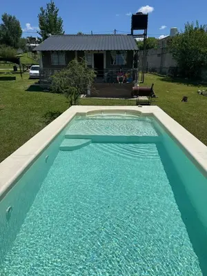 a swimming pool with blue water in a yard at El Parador de Tanti in Tanti