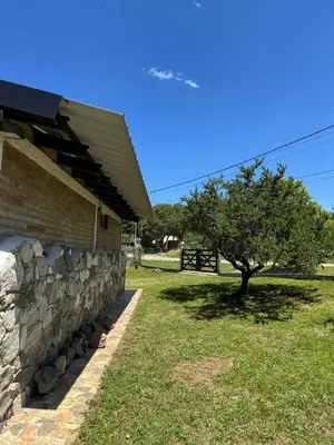 a building with a stone wall and a tree at El Parador de Tanti in Tanti