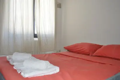 a bed with red sheets and white towels on it at Bellísimo apartamento con vistas a la ciudad in La Porteña