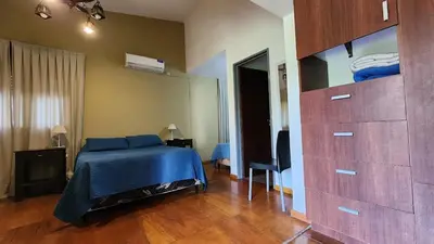 a bedroom with a bed with a blue blanket and a dresser at Habitaciones El Benteveo in Cordoba