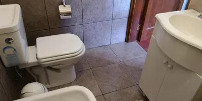 a bathroom with a white toilet and a sink at Habitaciones El Benteveo in Cordoba