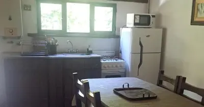 a kitchen with a table and a white refrigerator at Rincón de Paz in Los Reartes