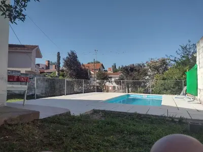 a swimming pool in a yard next to a fence at Refugio Serrano Carlos Paz parque y pileta privada in Villa Carlos Paz
