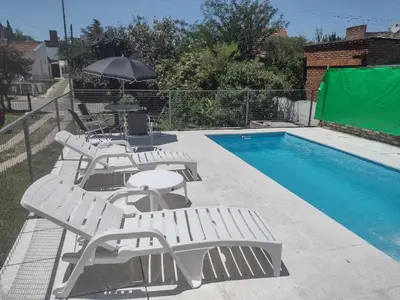a group of white lounge chairs next to a swimming pool at Refugio Serrano Carlos Paz parque y pileta privada in Villa Carlos Paz