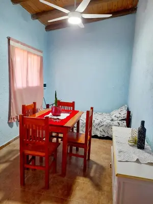 a dining room with a table and chairs and a bed at Brisas de las Sierras 2 in Tanti