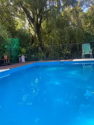 a blue swimming pool with a chair next to a fence at Siempre verde1 in El Rincón