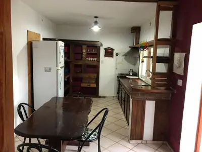 a kitchen with a table and a white refrigerator at El Sauce casa de verano in Mina Clavero