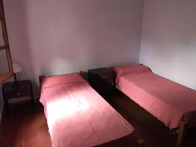 two beds in a small room with pink sheets at El Sauce casa de verano in Mina Clavero