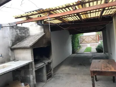 an outdoor patio with a wooden roof and a table at El Sauce casa de verano in Mina Clavero