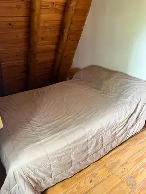 a small bed in a room with wooden floors at Cabañas La Juana in San Luis