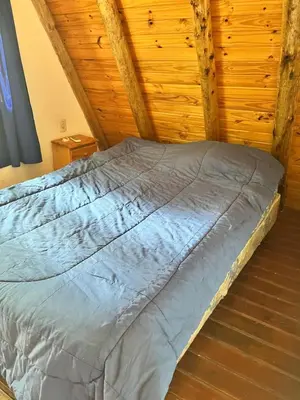 a bed in a room with a wooden ceiling at Cabañas La Juana in San Luis