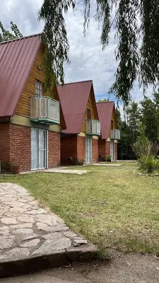 two houses with red roofs and a grass yard at Cabañas La Juana in San Luis