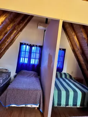 a bedroom with a bed and two windows at Cabañas La Juana in San Luis