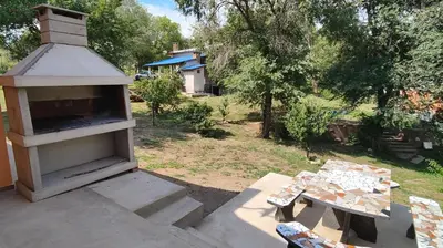 an outdoor oven with a table and a bench at Cabaña Cecilia II in Villa Icho Cruz