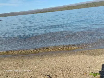 a beach with a body of water and the ocean at Cabañas Refugio del Alma in Villa Amancay