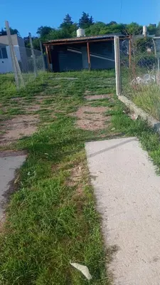 a field of grass next to a fence and a sidewalk at La casita de Nestor in Cavalango