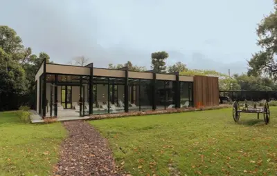 a building in a field with a bench in the grass at La urumpta hotel aken mind in Río Cuarto