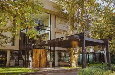 a large building with a wooden door and a tree at La urumpta hotel aken mind in Río Cuarto