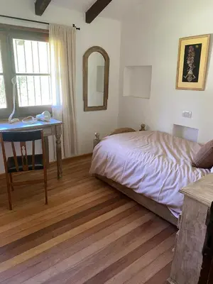 a bedroom with a bed and a table and a mirror at Casa de Campo in Los Hornillos