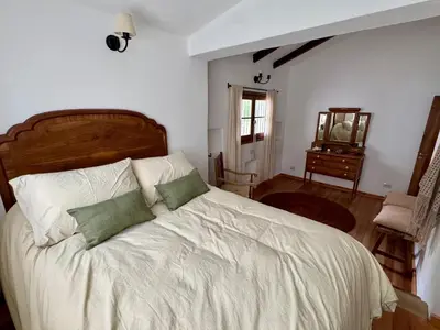 a bedroom with a bed with white sheets and green pillows at Casa de Campo in Los Hornillos