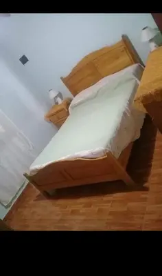a bedroom with a wooden bed with white sheets and pillows at Complejo El Trencito in Villa Cura Brochero
