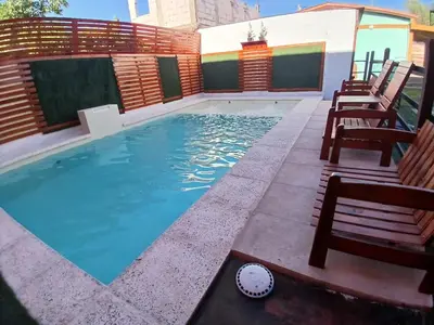 a swimming pool in a backyard with chairs around it at Complejo El Trencito in Villa Cura Brochero