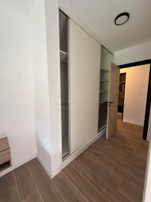 a walk in closet with glass doors and wood flooring at depto carlos paz in Villa Carlos Paz