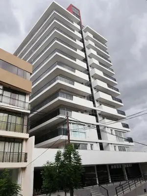 a tall white building with a red sign on it at Departamento Edificio Leonardo 1 in Villa Carlos Paz