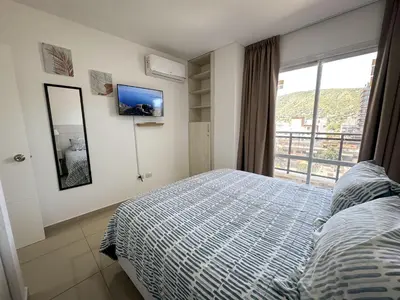 a bedroom with a bed and a large window at Departamento Edificio Leonardo 1 in Villa Carlos Paz
