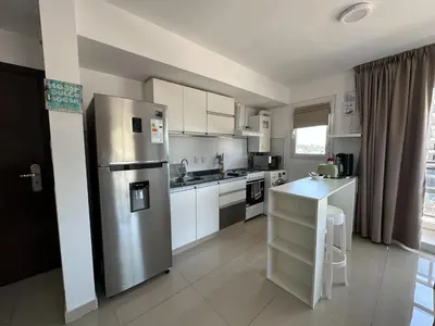 a kitchen with a stainless steel refrigerator and white cabinets at Departamento Edificio Leonardo 1 in Villa Carlos Paz