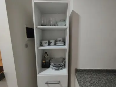 a white pantry with plates and dishes on shelves at Mi Espacio Departamento en Alta Gracia in Alta Gracia