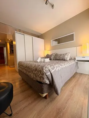 a bedroom with a large bed and a black chair at Departamento 8 Villa Carlos Paz in Villa Carlos Paz