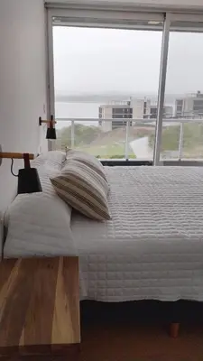 a bedroom with a bed with a large window at departamento en Lago Los Molinos in Villa Ciudad de America
