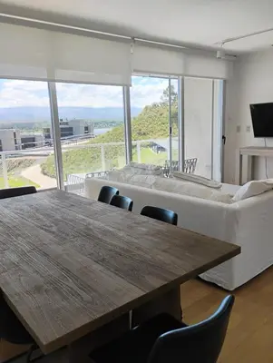 a living room with a wooden table and a couch at departamento en Lago Los Molinos in Villa Ciudad de America