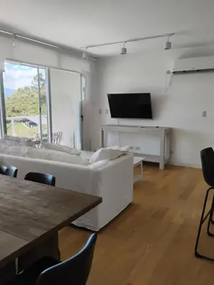 a living room with a couch and a tv and a table at departamento en Lago Los Molinos in Villa Ciudad de America
