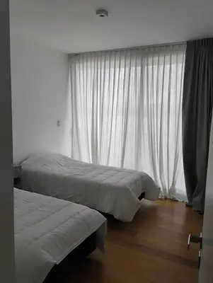 two beds in a room with white curtains at departamento en Lago Los Molinos in Villa Ciudad de America