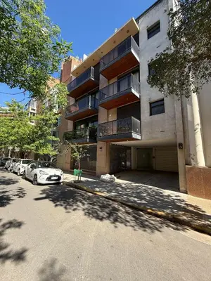 a building with cars parked in a parking lot at Thays Apartment in Cordoba