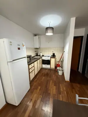 a kitchen with a white refrigerator and wooden floors at Thays Apartment in Cordoba