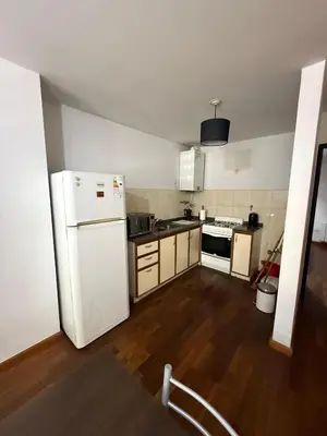 a kitchen with a white refrigerator and wooden floors at Thays Apartment in Cordoba
