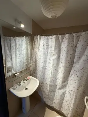 a bathroom with a sink and a white shower curtain at Thays Apartment in Cordoba