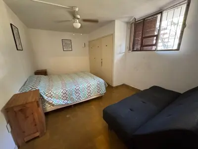 a bedroom with a bed and a couch and a window at Patio Serrano - Casa privada en planta baja in Villa Carlos Paz