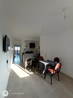 a living room with a table and chairs and a kitchen at Home Rio Cuarto 