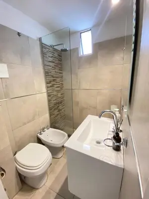 a white bathroom with a toilet and a sink at Departamento 3 centro villa carlos paz in Villa Carlos Paz