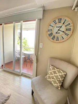 a clock hanging on a wall next to a chair at Departamento 3 centro villa carlos paz in Villa Carlos Paz