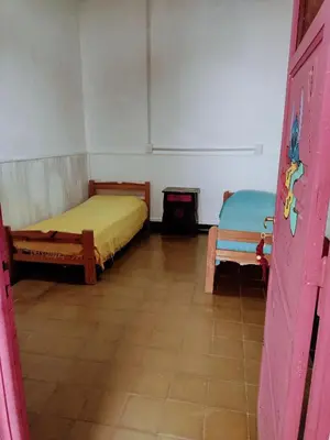 a room with two beds and a chair in it at Casona La Ventanita in Mina Clavero
