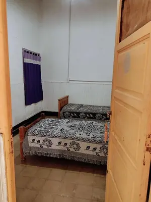 two beds in a small room with a door at Casona La Ventanita in Mina Clavero
