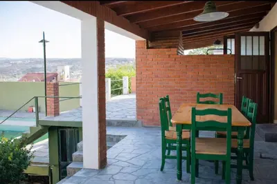 a patio with a wooden table and chairs on a balcony at Casa con pileta in Villa Carlos Paz